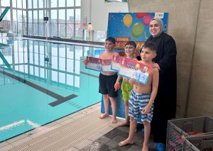 3 kinderen showen trots hun zwemdiploma samen met de wethouder