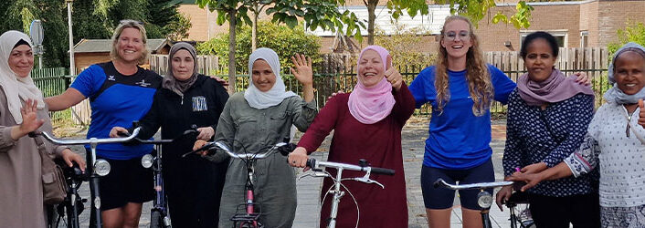 Vrouwen staan op een schoolplein poserend in een rij met fietsen