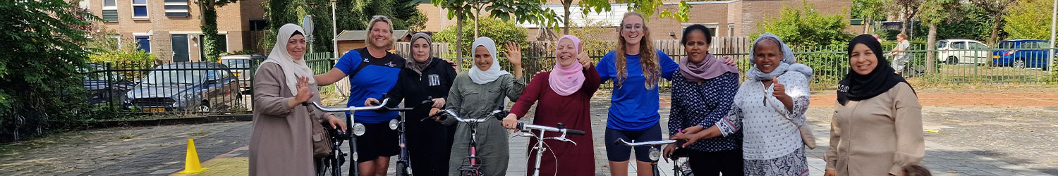 Vrouwen staan op een schoolplein poserend in een rij met fietsen