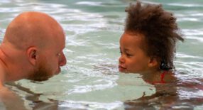 vader en dochter spelen samen in het water en blazen water naar elkaar