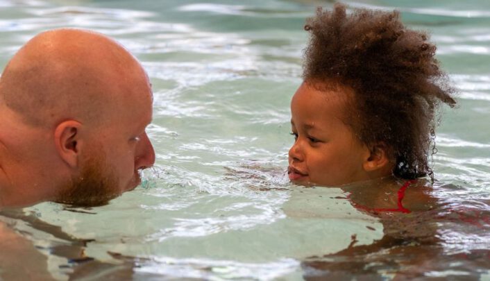 vader en dochter spelen samen in het water en blazen water naar elkaar