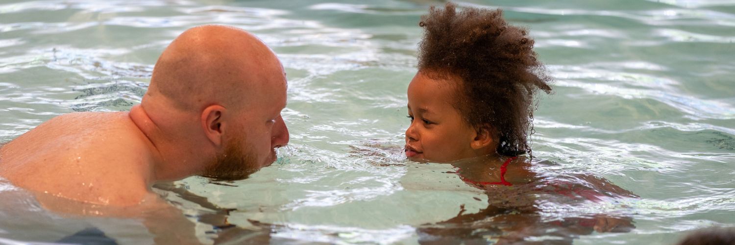 vader en dochter spelen samen in het water en blazen water naar elkaar