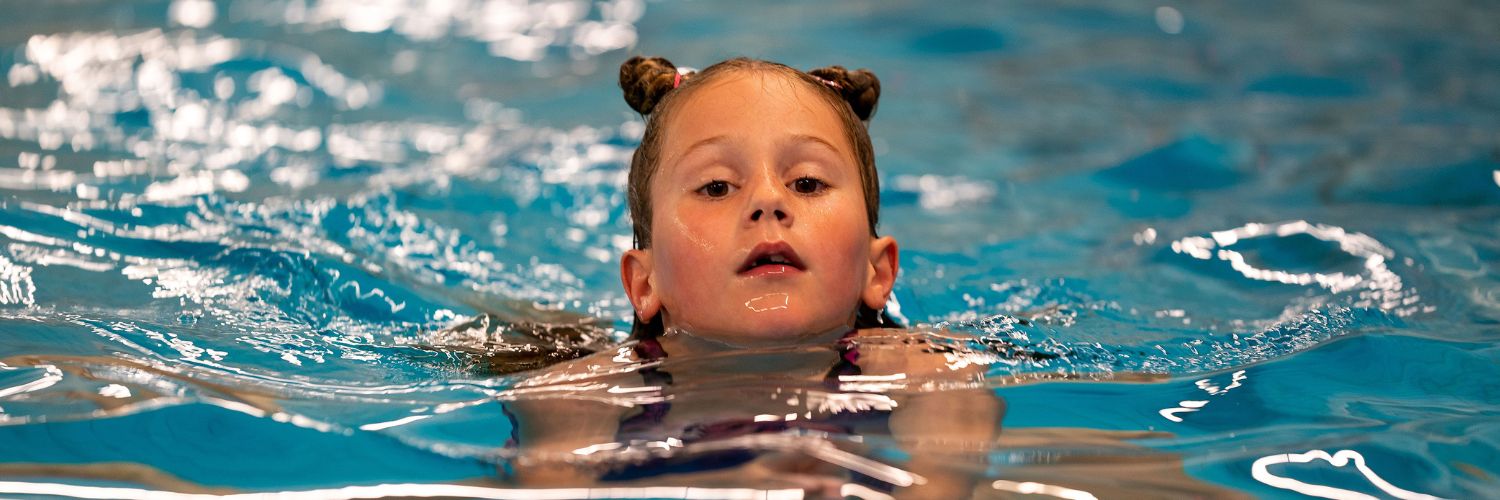 meisje met knotjes zwemt schoolslag