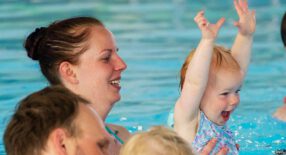 Moeder en kindje spelen in het water, kindje heeft de armpjes in de lucht gestoken