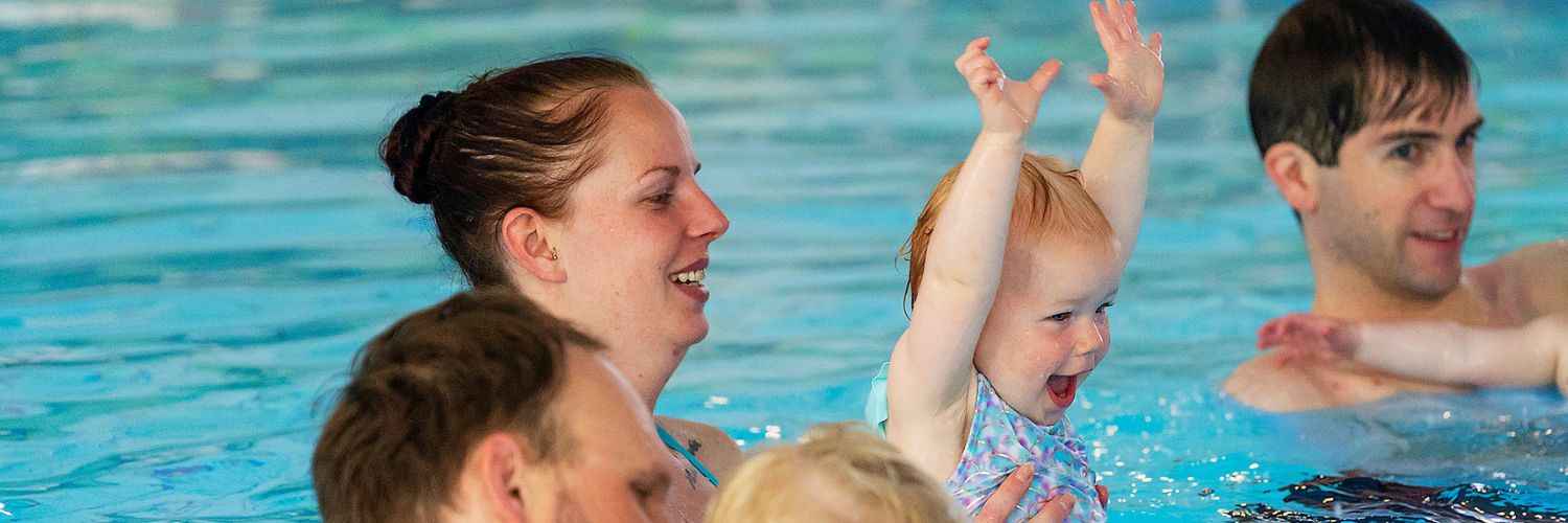 Moeder en kindje spelen in het water, kindje heeft de armpjes in de lucht gestoken