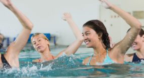 groepje Dames staat in het water en heeft allemaal de linker arm in de lucht
