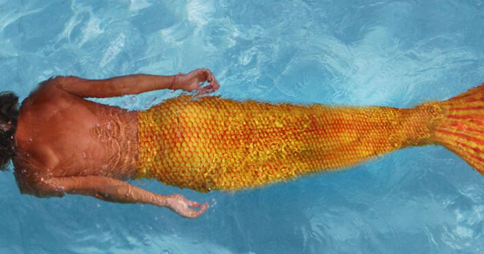 zeemeerman zwemt onder water met een oranje zwemstaart