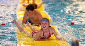 kinderen die op een mat aan het spelen zijn in het water.
