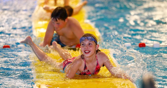kinderen die op een mat aan het spelen zijn in het water.
