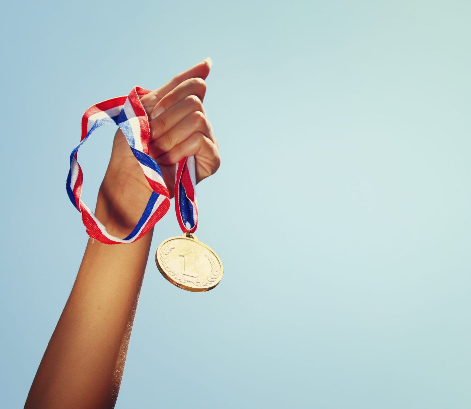 Hand houdt medaille waar Nummer 1 op staat in de lucht