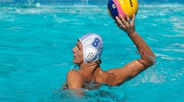 waterpolo'er in het zwembad werpt de bal met zijn rechtgerhand omhoog